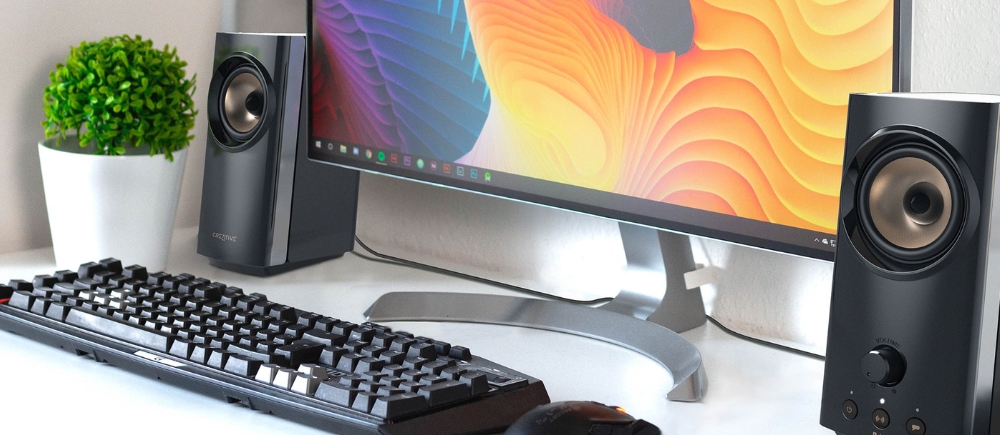 Głośniki komputerowe Creative T60 Bluetooth 5.0 pod skosem obok monitora 