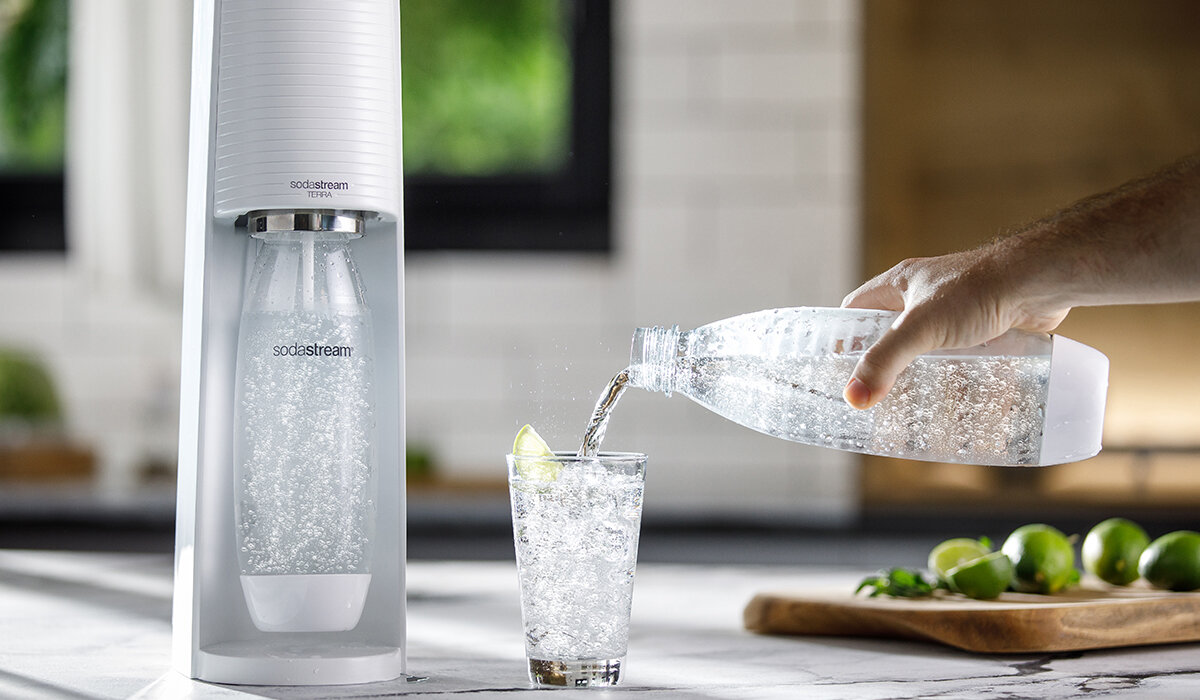 Butelki SodaStream Fuse 2x1L Białe widok na saturator i butelke z napojem trzymaną w ręku