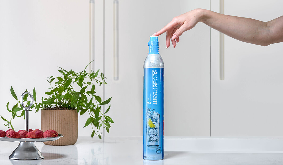 Cylinder SodaStream Twist Connect niebieski widok od frontu na rękę dotykającą nabój