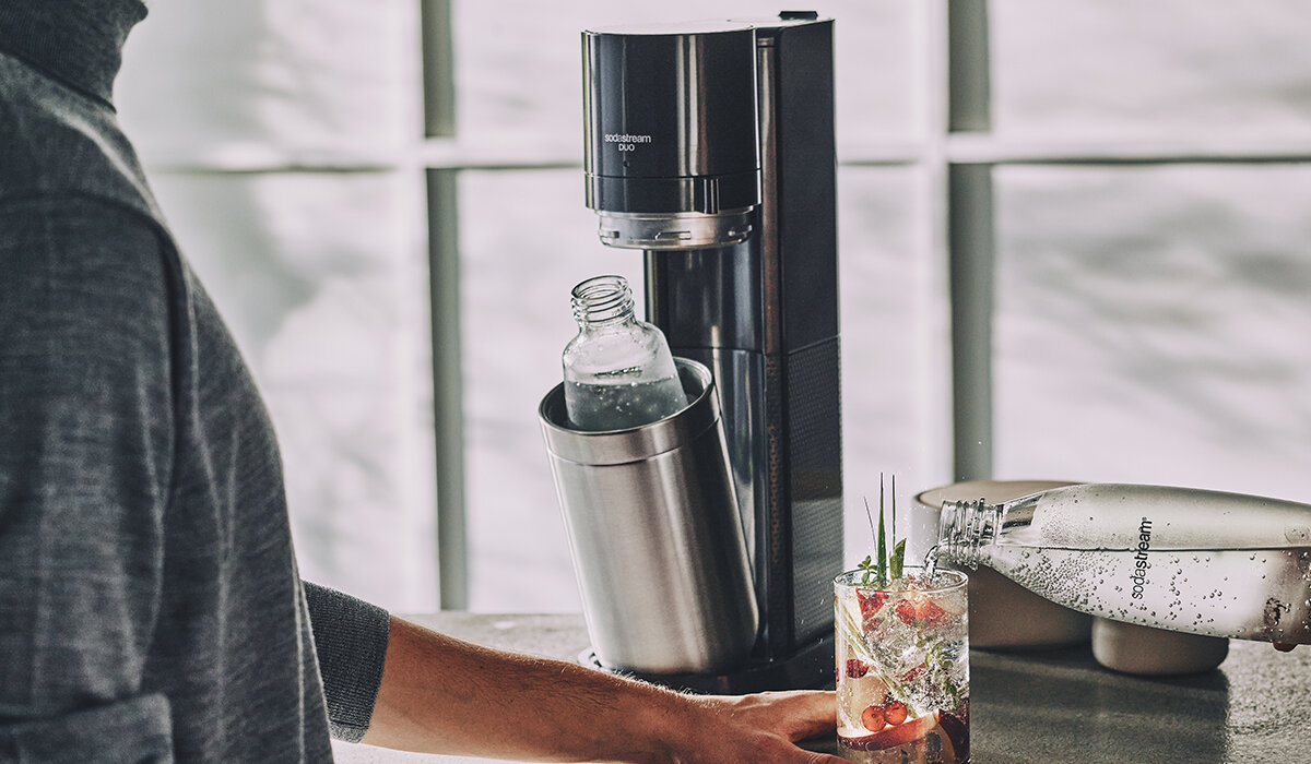 Ekspres SodaStream Duo Czarny widok na gotowy napój i urządzenie na tle kuchni