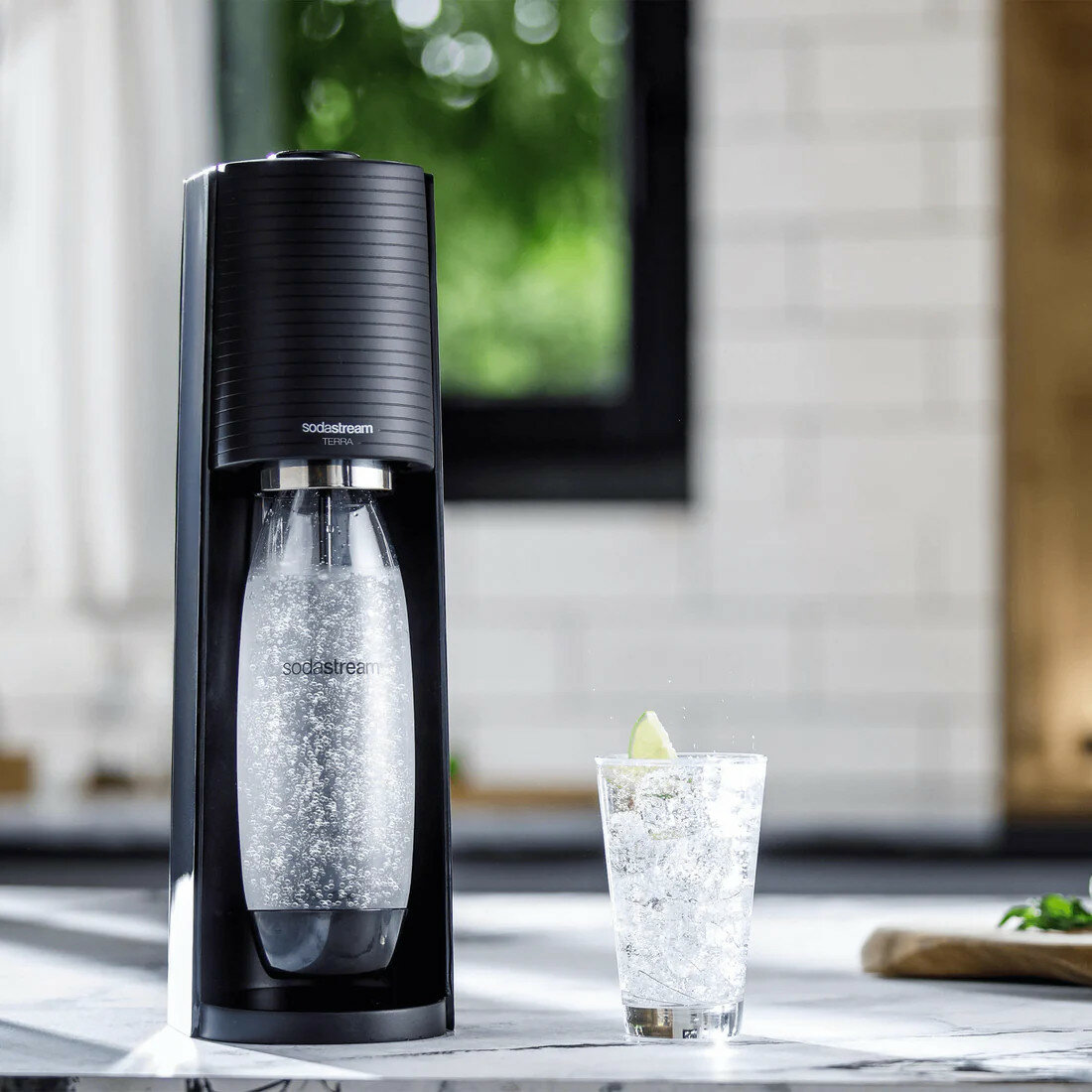 Ekspres SodaStream Terra Czarny 3 butelki z gotowym napojem na tle kuchni