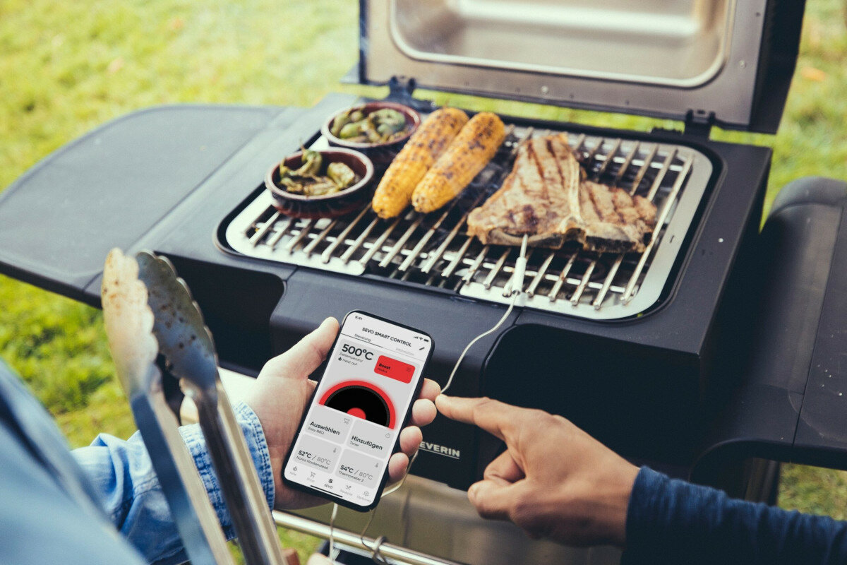 Grill Severin Sevo Smart Control GT PG8138 czarny widok na aplikacje w telefonie na tle grilla