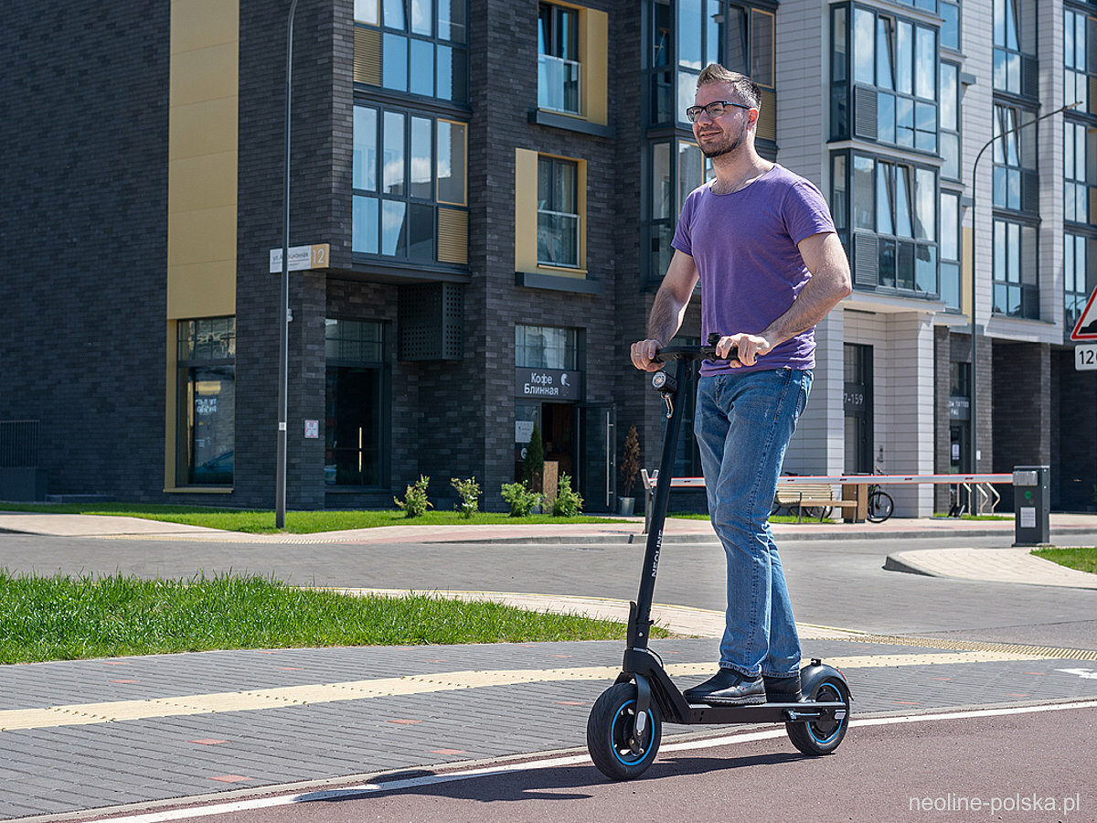 Hulajnoga elektryczna Neoline Scooter T26 350W pan jadący na hulajnodze