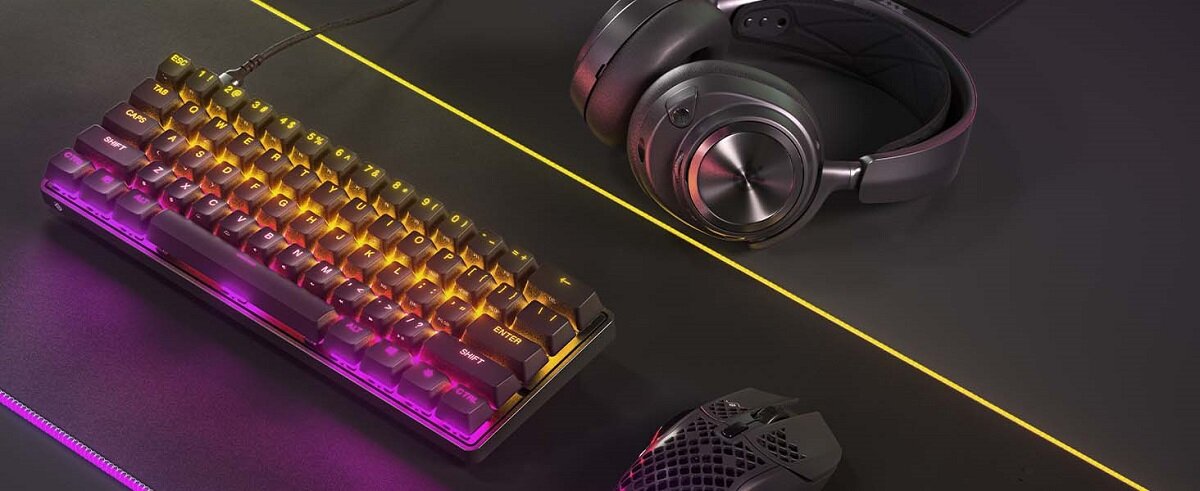 Klawiatura SteelSeries Apex 9 Mini US na stole obok myszki i słuchawek