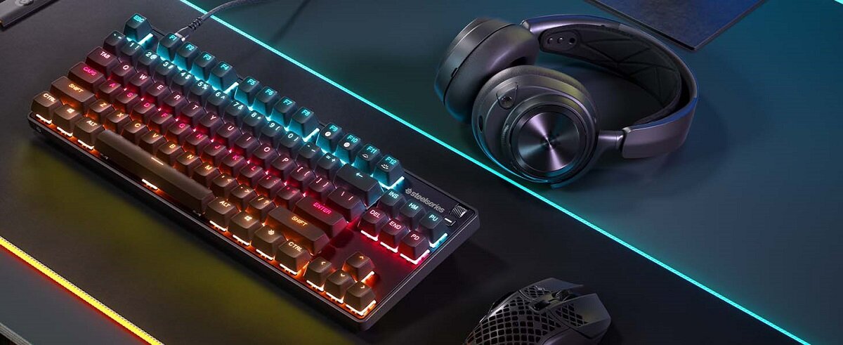 Klawiatura SteelSeries Apex 9 TKL US na stole obok myszki i słuchawek