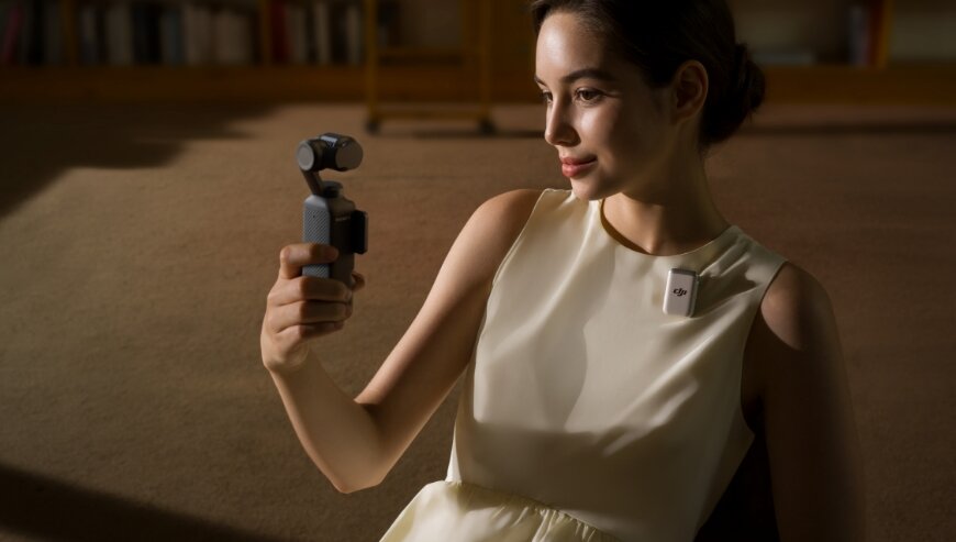 Nadajnik DJI Mic 2 grafika przedstawia kobietę trzymającą kamerę dji oraz nadajnik przyczepiony do jej bluzki