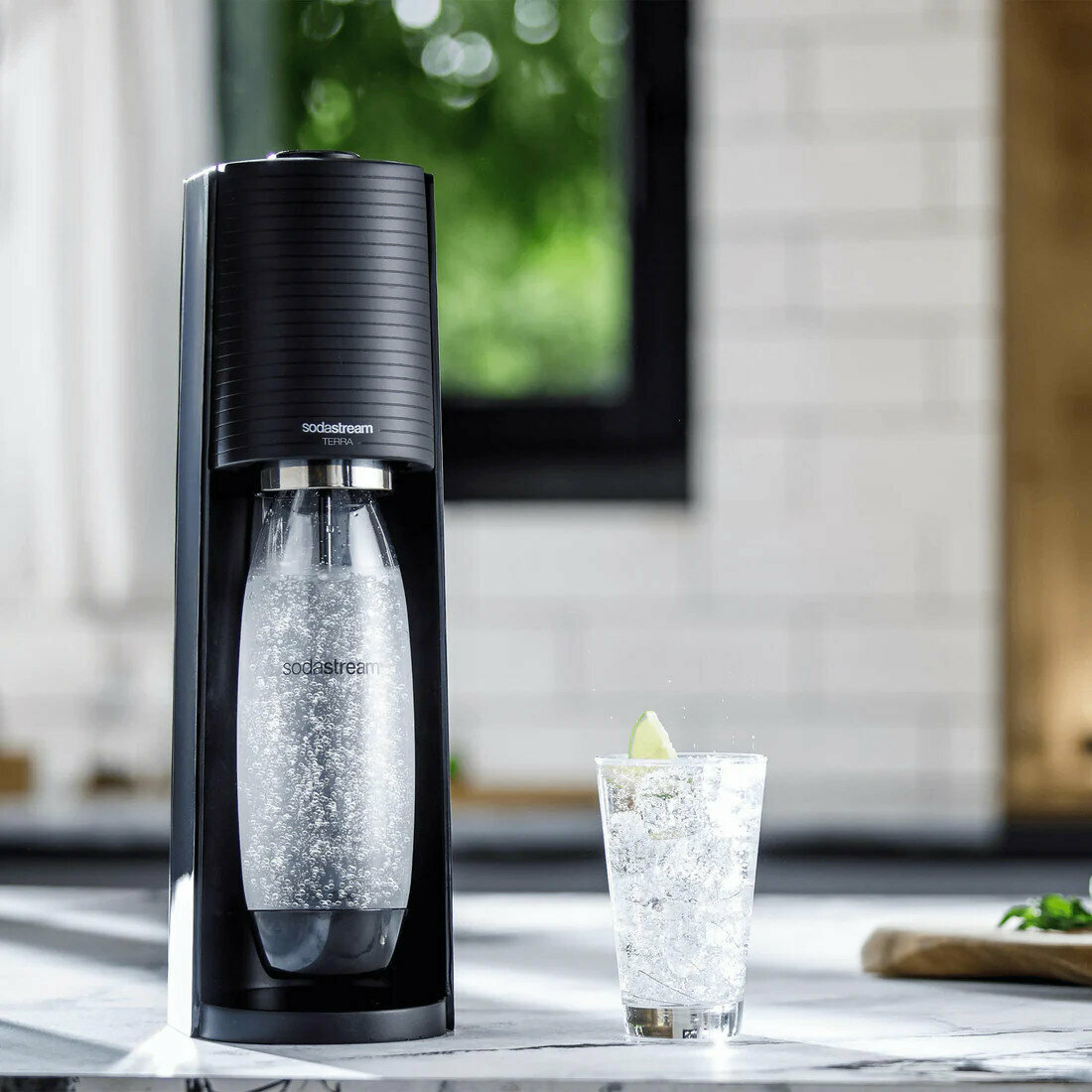 Saturator SodaStream Terra czarny 3 butelki z gotowym napojem na tle kuchni