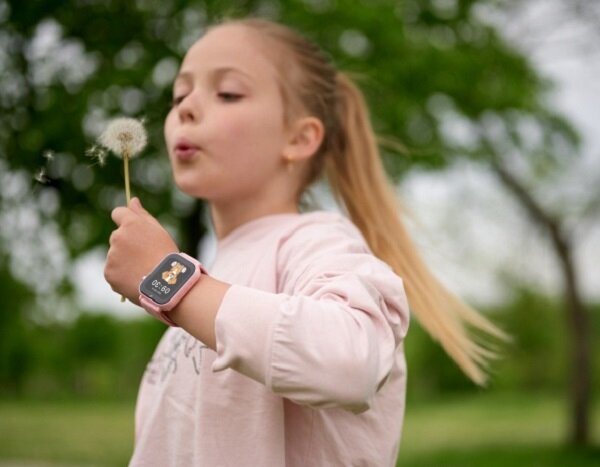 Smartwatch Garett Kids N!ce Pro 4G dziewczynka z kwiatkiem w ręku oraz z zegarkiem na nadgarstku