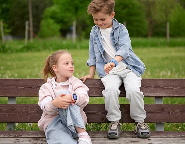 Smartwatch Garett Kids Sun Ultra 4G dzieci siedzące na ławce ze smartwatchami na rękach