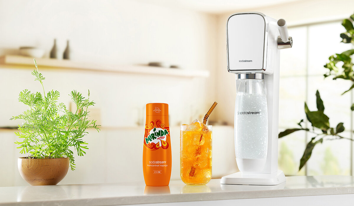 Syrop SodaStream Mirinda 440ml widok na butelkę syropu, gotowy napój oraz urządzenie na tle kuchni 