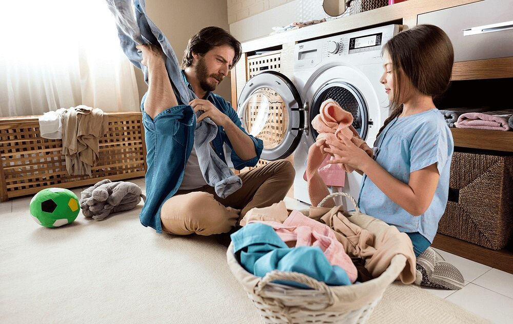Pralka do zabudowy Beko WITC 7612 B0W widok na dziewczynkę i mężczyznę podczas szykowania ubrania do prania w pralce