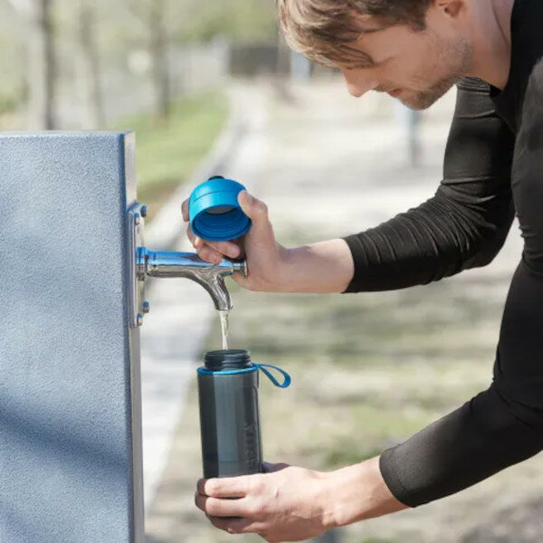 Wkład filtrujący Brita MicroDisc widok na mężczyznę który nalewa wodę do butelki z dystrybutora