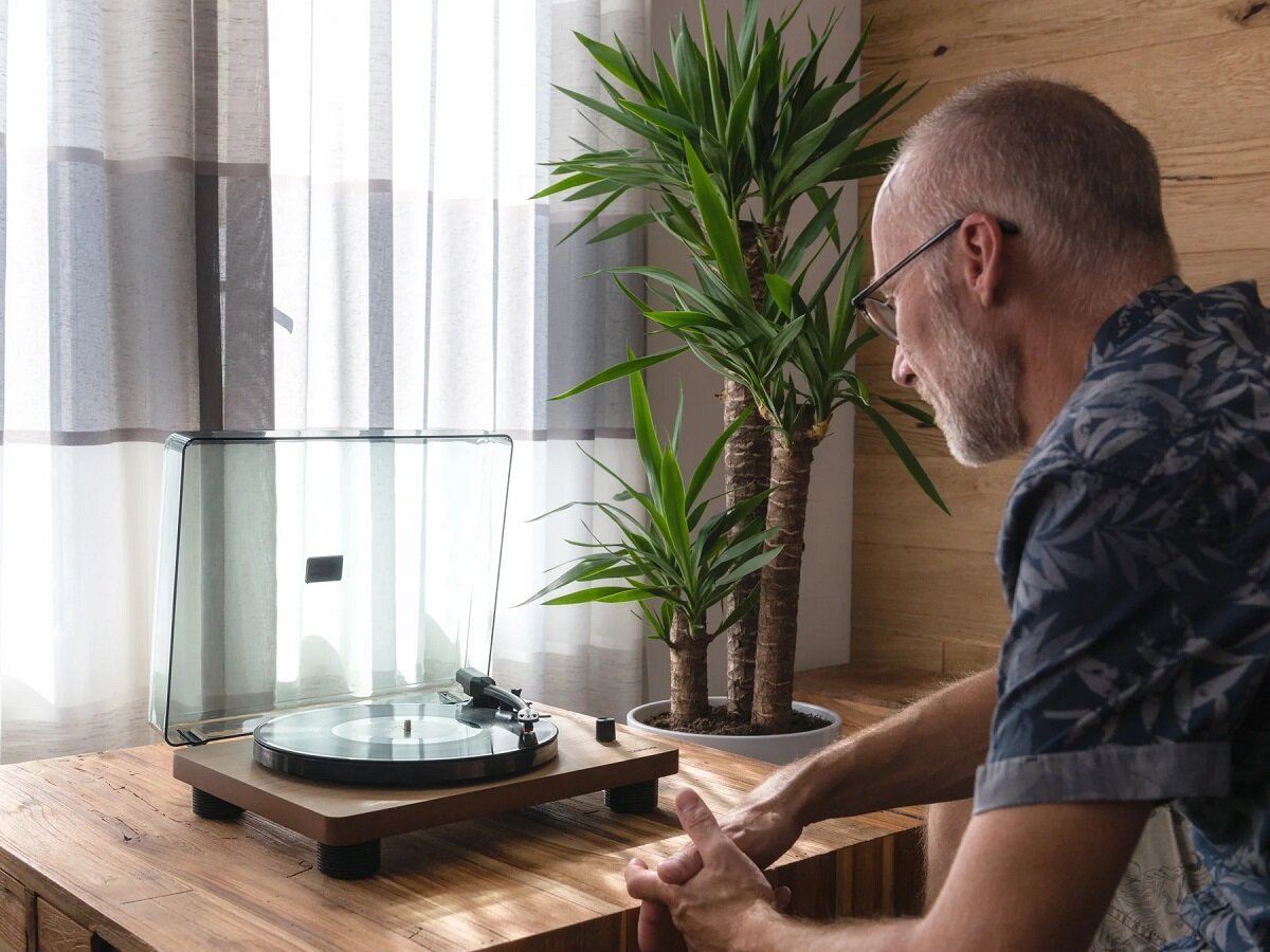 Gramofon Lenco LS-50 WD 50-60 Hz na stoliku w pokoju z mężczyzną obok