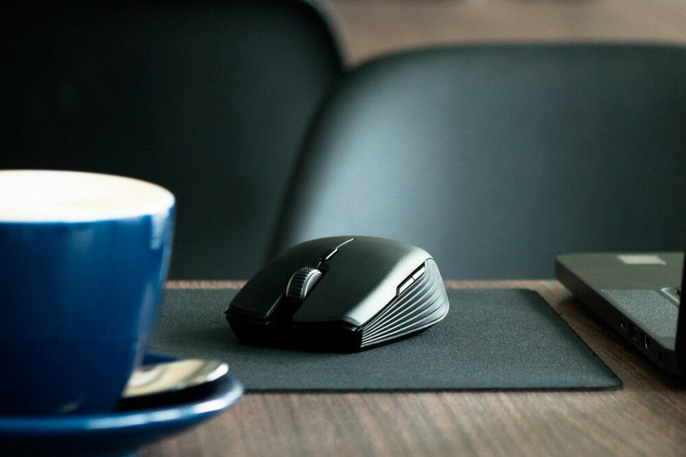 Mysz Razer Atheris - Czarny mysz na podkładce przy laptopie, obok niebieska filiżanka