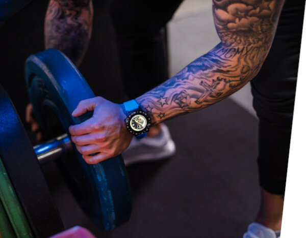 Smartwatch Garett Multi 4 Sport na dłoni mężczyzny dokładającego ciężar do sztangi na siłowni