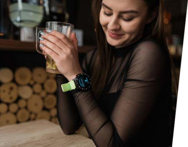 Smartwatch Garett Multi 4 Sport na dłoni kobiety siedzącej w restauracji patrzącej na wyświetlane powiadomienie na zegarku