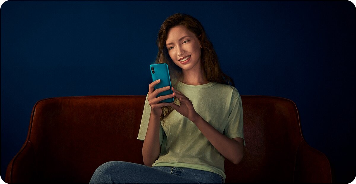 Smartfon Xiaomi Redmi 9A 32GB Szary w rękach kobiety siedzaćej na kanapie