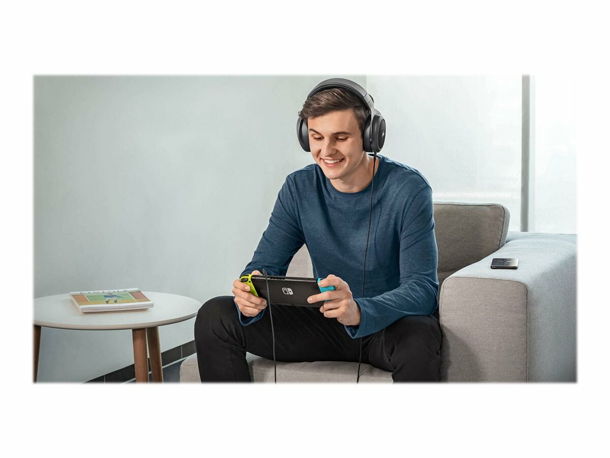 Słuchawki Corsair HS70 CA-9011227-EU mężczyzna w słuchawkach grający na konsoli przenośnej