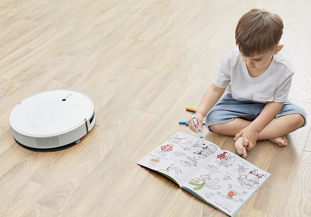 Robot sprzątający Dreame F9 dziecko rysujące na podłodze, obok odkurzacz