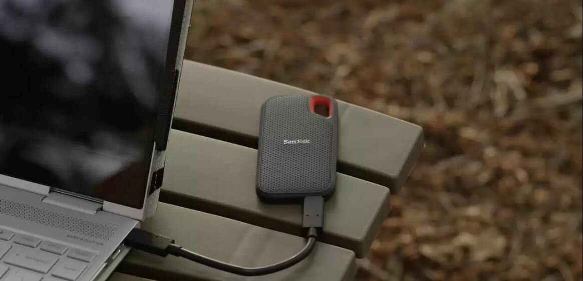 Dysk SSD Sandisk Extreme Portable 500GB SDSSDE60-500G-G25  dysk podłączony do laptopa na ławce w parku