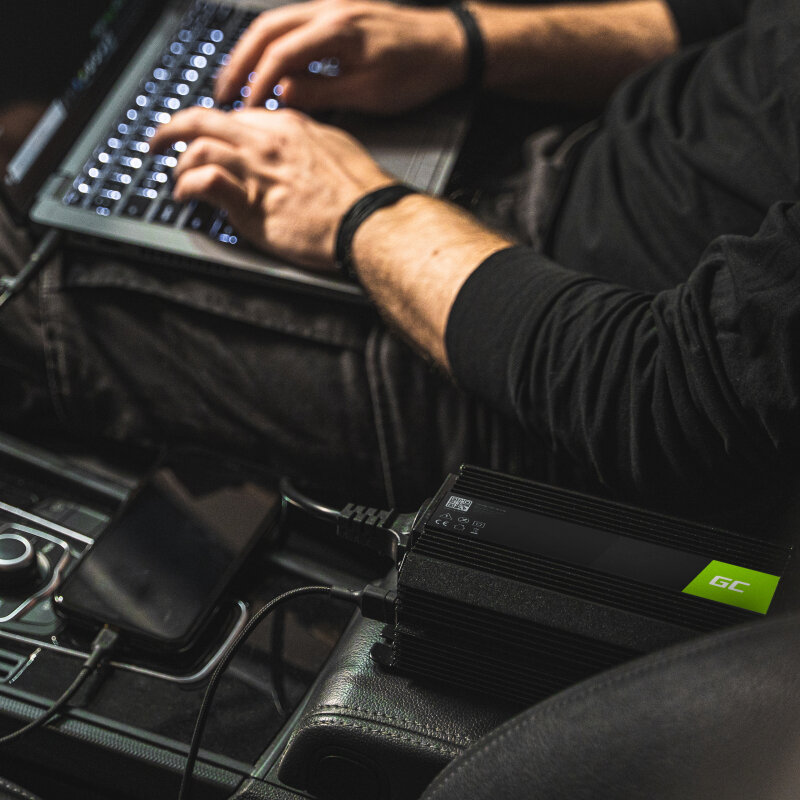 Przetwornica napięcia Green Cell Inwerter 12V na 230V czarna podłączony do telefonu i laptopa, mężczyzna piszący na klawiaturze