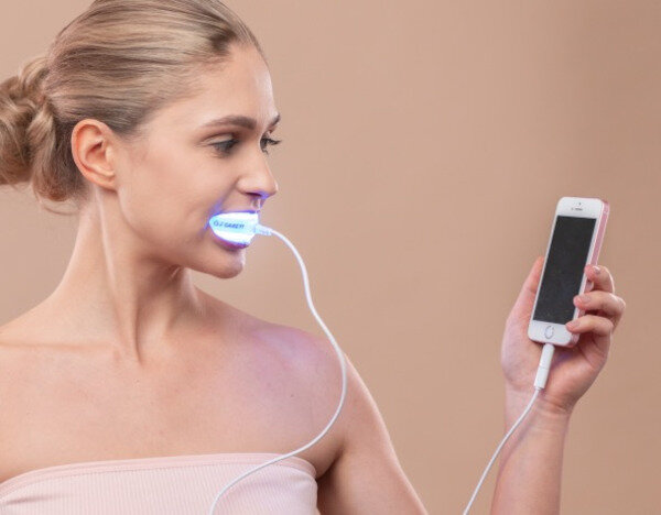 Lampa do wybielania zębów Garett Beauty Smile Connect widok na włączoną lampę podłączoną do telefonu