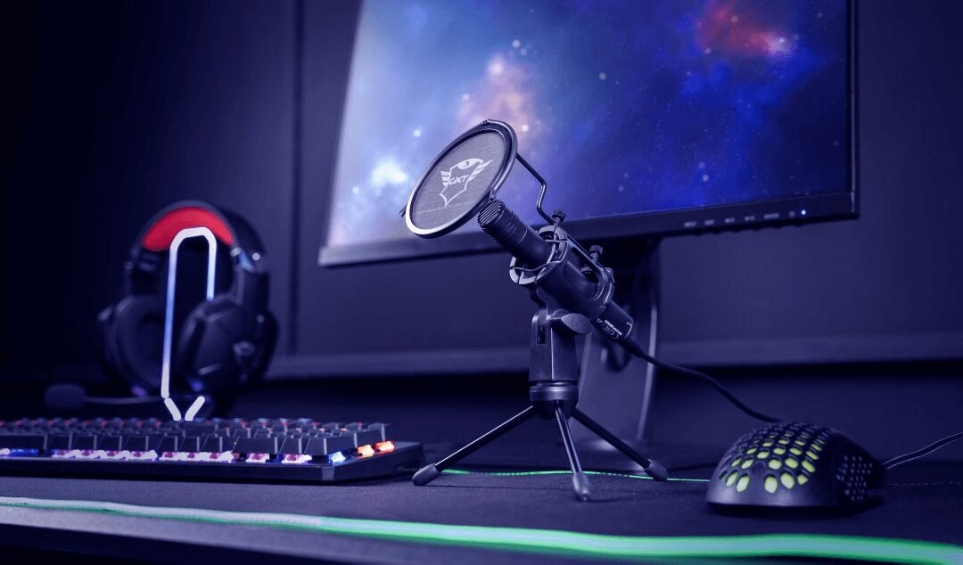 Mikrofon streamingowy Trust GXT 241 Velica stojący na biurku pod skosem w lewo obok klawiatury i nóżki monitora