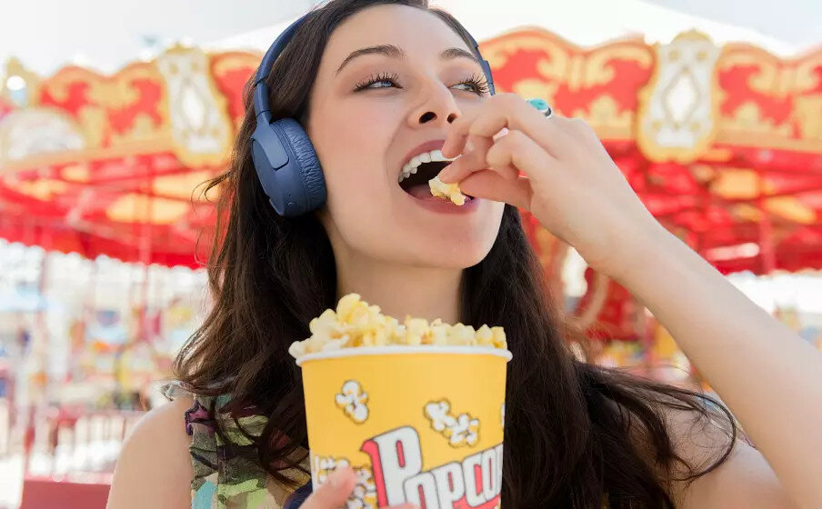 Słuchawki bezprzewodowe JBL Tune 510BT widok na kobietę z popcornem i słuchawkami