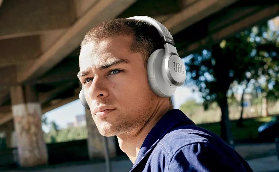 Słuchawki JBL Live 660NC LIVE660NCBLK mężczyzna z białymi słuchawkami na uszach jedna słuchawka widoczna od boku