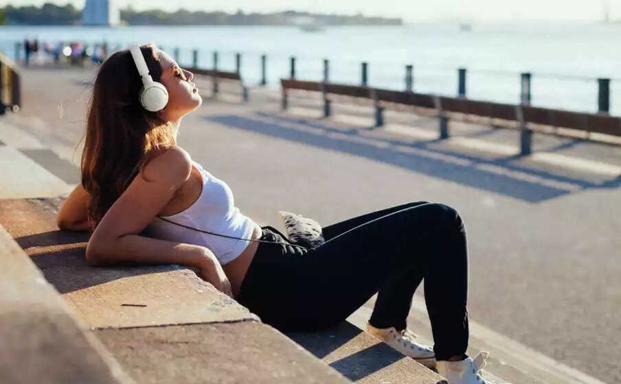Słuchawki bezprzewodowe JBL Tune 660BT widok na kobietę chillującą na schodach w słuchawkach