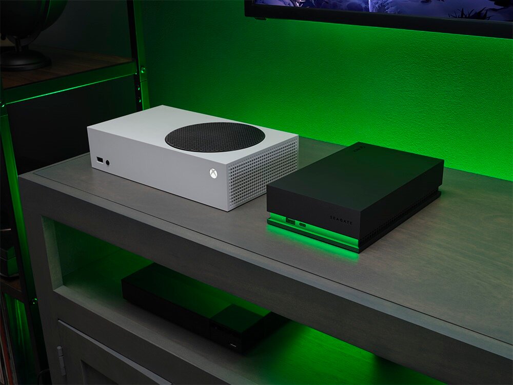 Dysk do konsoli Xbox Seagate Game Drive STKW8000400 8TB w towarzystwie konsoli xbox na półce pod telewizorem 