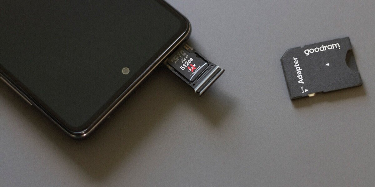 Karta pamięci Goodram M2AA-1280R12 128GB microSDXC UHS-I w slocie na kartę pamięci w telefonie na biurku