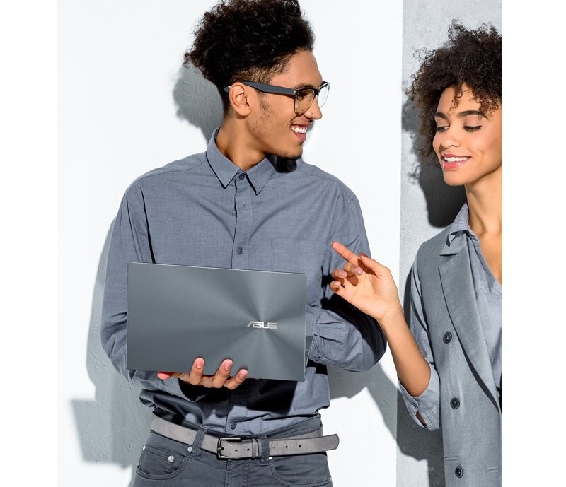 Laptop Asus ZenBook 14 UX425 UX425EA-KI391T widok na klapę laptopa trzymanego przez mężczyznę, który rozmawia z kobietą obok