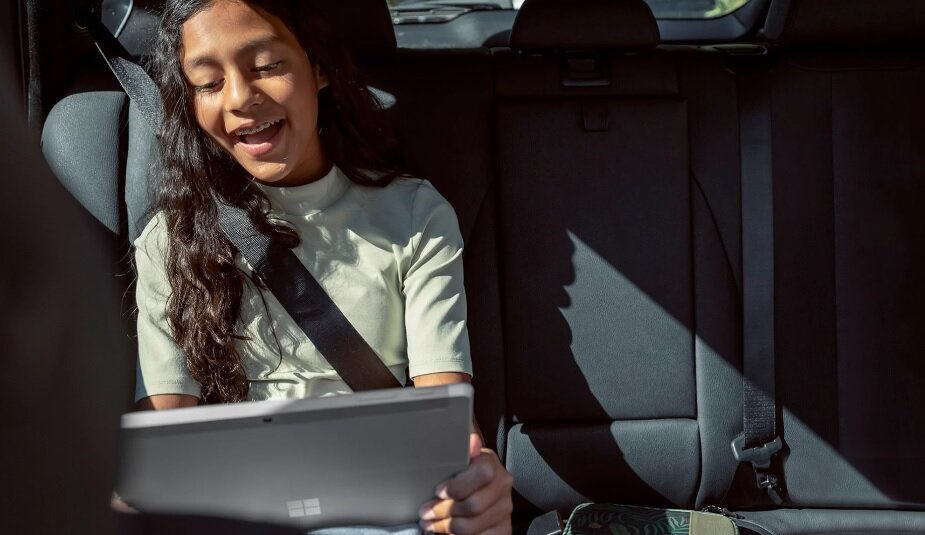 Tablet/laptop Microsoft Surface Go 3 - dziewczynka trzymająca urządzenie w samochodzie