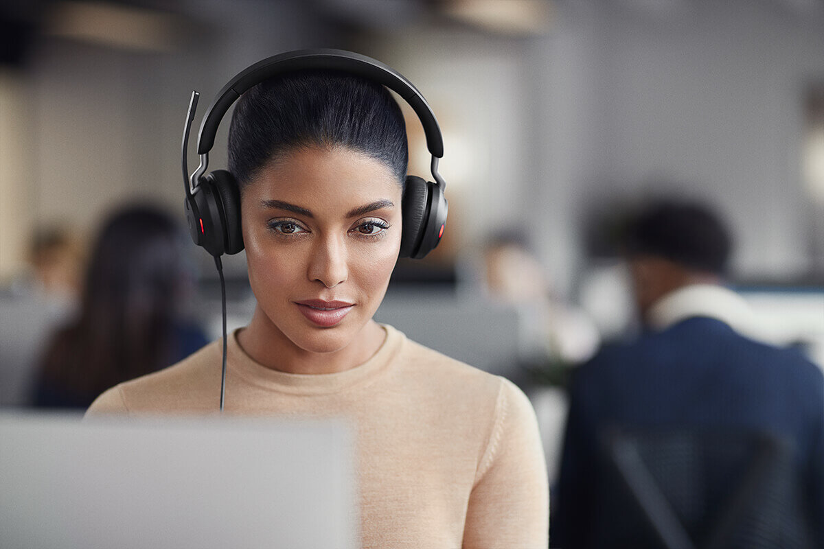 Słuchawki z mikrofonem Jabra Evolve2 40 USB-A MS stereo kobieta ze słuchawkami na uszach siedzaca przy laptopie