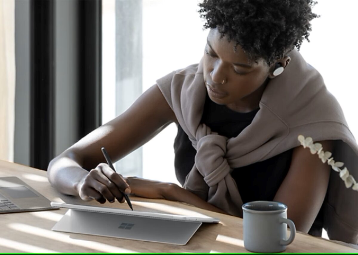 Laptop Microsoft Surface Pro 8 Intel Core i7-1185G7 platynowy kobieta siedząca przy stole pisząca piórem Slim Pen na ekranie laptopa