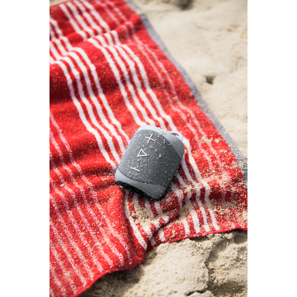 Głośnik bezprzewodowy Sharp GX-BT180(GR) Szary będący na ręczniku na plaży