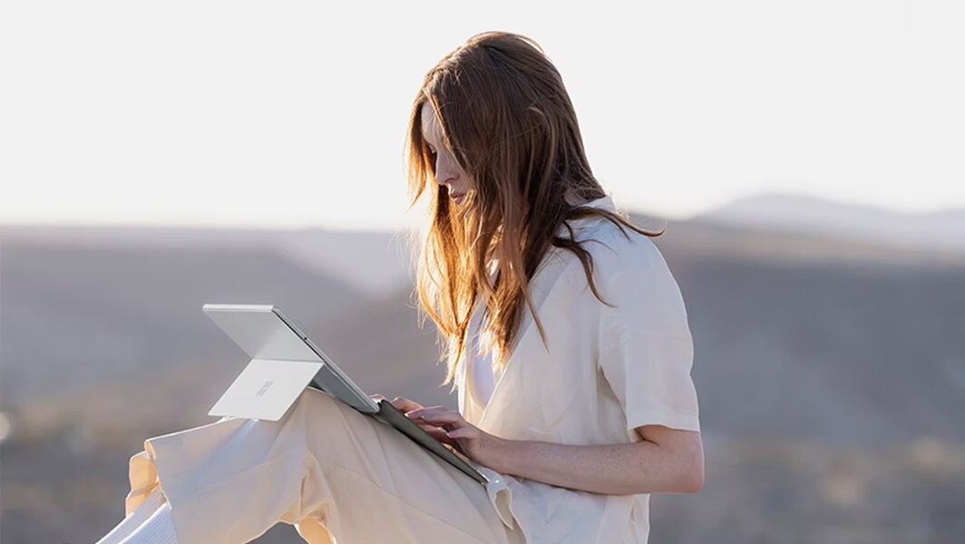 Klawiatura Microsoft Signature do Surface Pro z czytnikiem linii papilarnych, kobieta pracująca pisząca na klawiatiurze na tle gór