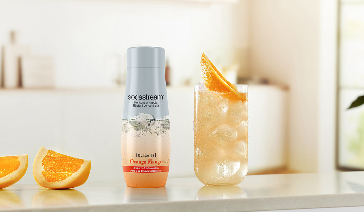 Syrop SodaStream Orange Mango Zero 440ml butelka syropu wraz z gotowym napojem na tle kuchni