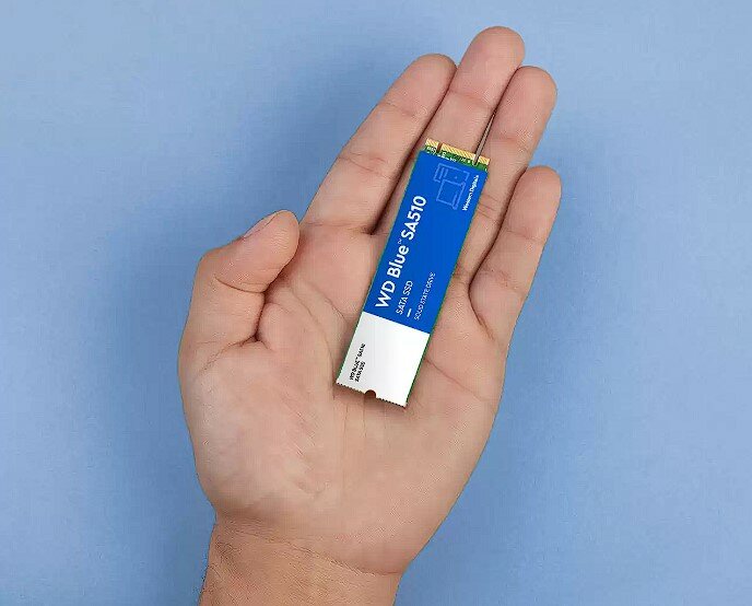 Dysk SSD WD Blue SA510 1TB SATA M.2 widok na dysk leżący na dłoni na niebieskim tle