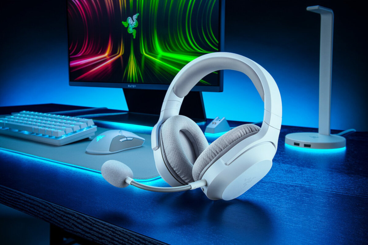 Słuchawki Razer Barracuda X białe grafika przedstawia słuchawki na biurku w tle monitor, klawiatura, mysz oraz stojak na słuchawki