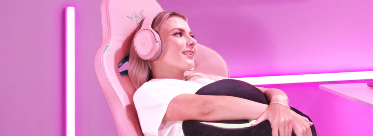 Słuchawki Razer Barracuda X białe grafika przedstawiająca kobietę siedzącą w fotelu ze słuchawkami na uszach na różowym tle