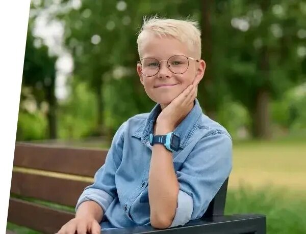 Smartwatch Garett Kids Twin 4G widok na chłopca siedzącego na ławce z widocznym smartwatchem na nadgarstku