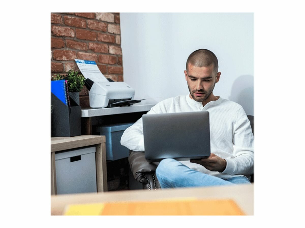 Skaner Brother ADS-4100 biały mężczyzna pracujący na laptopie ze skanerem w tle