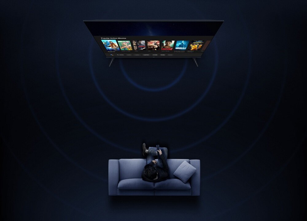 Telewizor Xiaomi Mi LED TV A2 widok od góry na telewizor i mężczyznę siedzącego z pilotem w ręku na kanapie przed telewizorem