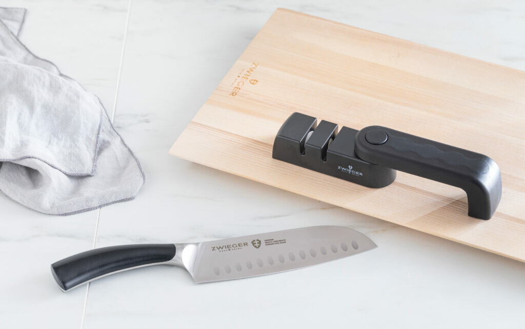Ostrzałka do noży Zwieger Practi Plus widok na ostrzałkę na blacie kuchennym na desce i nóż obok