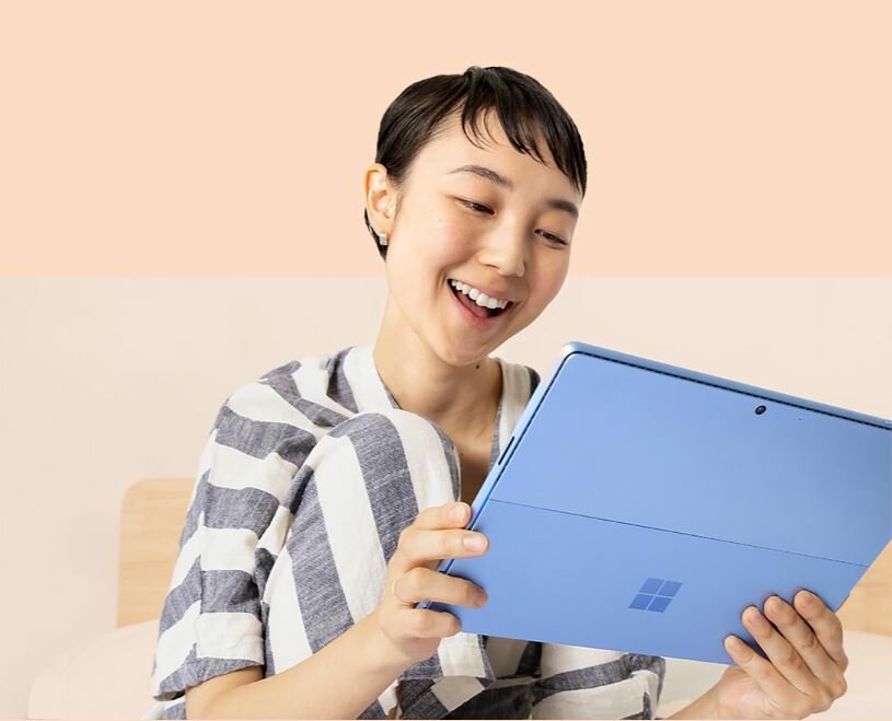 Laptop Microsoft Surface Pro 9 8GB/128GB 5G grafika przedstawia uśmiechniętą kobietę trzymającą w rękach laptopa