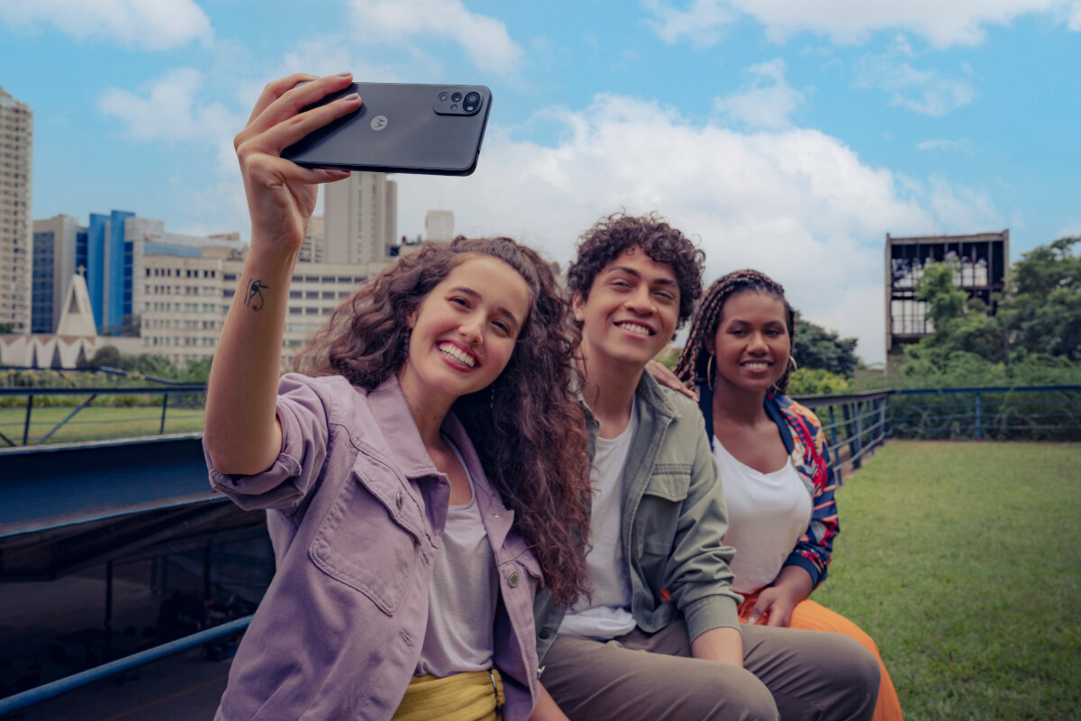 Smartfon Motorola moto g22 od boku w ręce kobiety robiącej selfie sobie i przyjaciołom