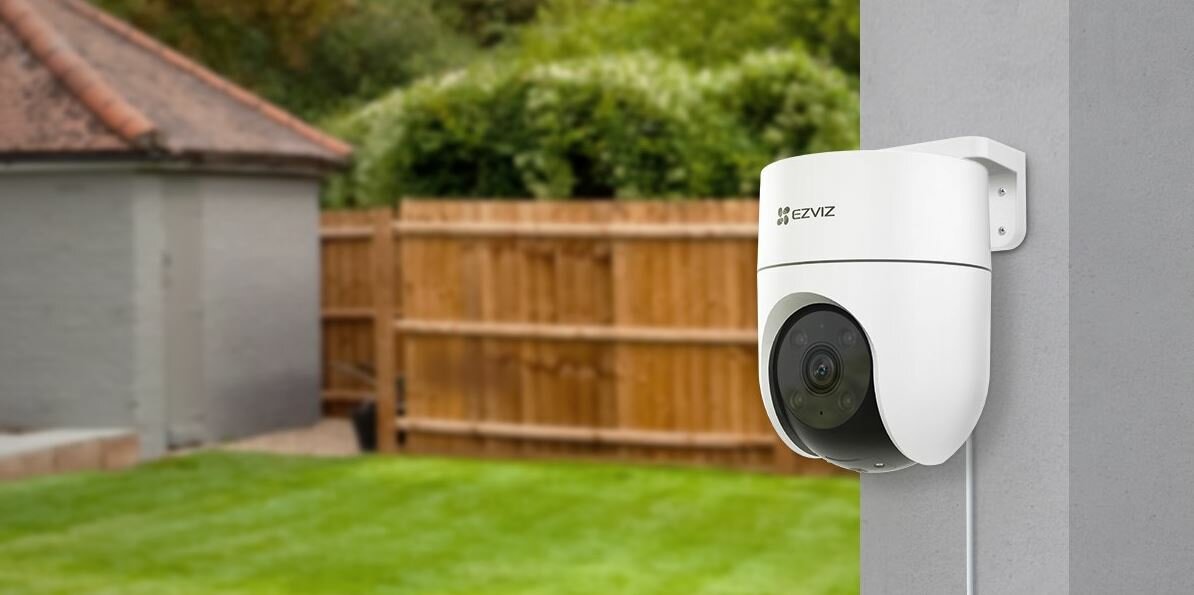 Kamera Ezviz H8c 1080p zamontowana na słupie na tle ogrodu