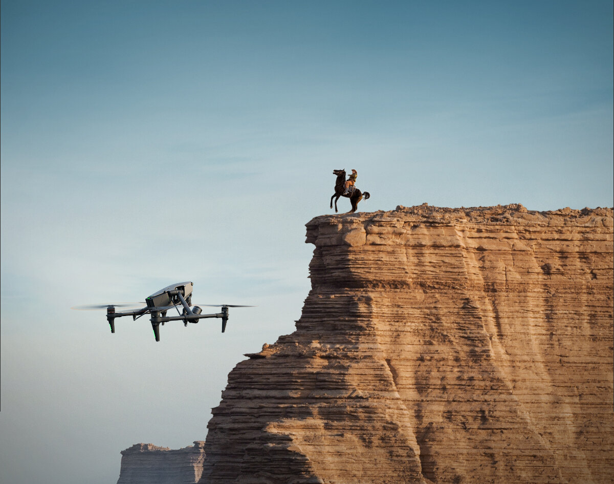 Dron DJI Inspire 3 94 km/h dron unoszący się w powietrzu na tle wysokiej skały, na której jest koń
